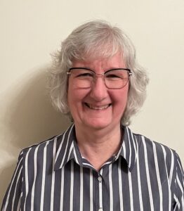 Smiling person in striped shirt and glasses.