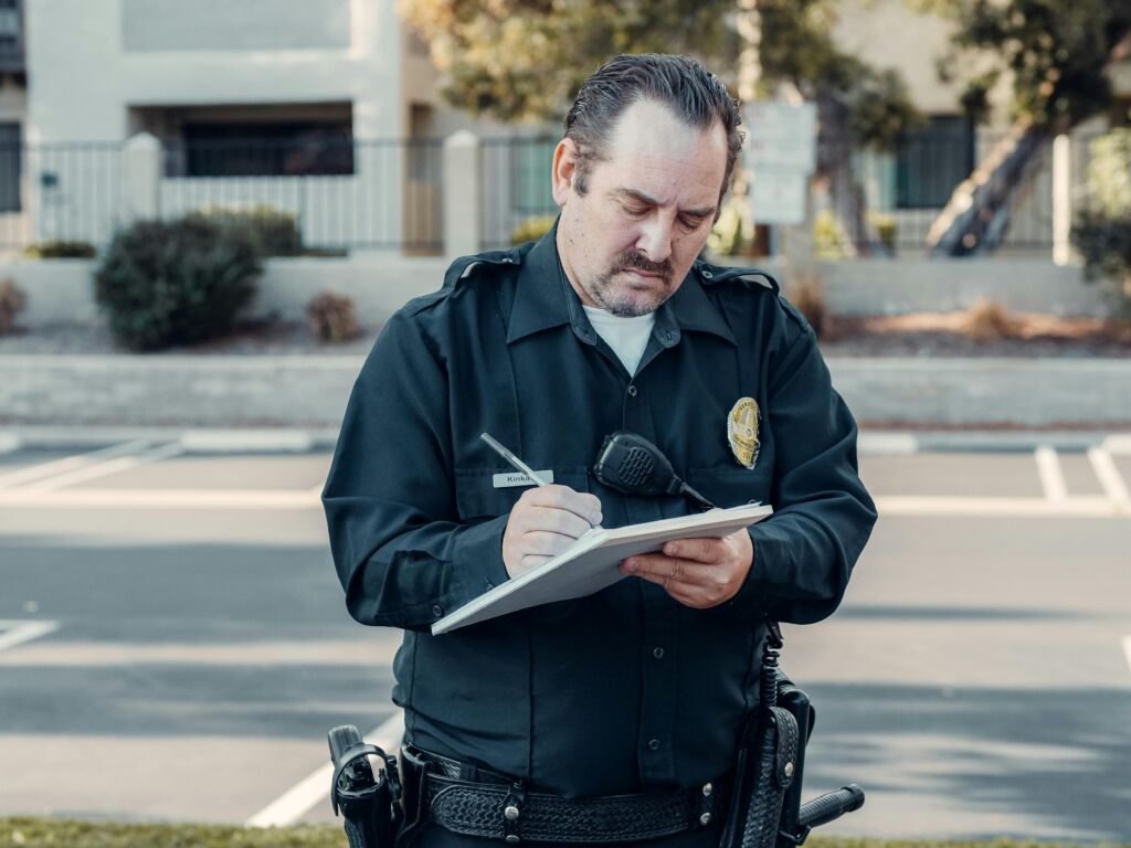 Police officer writing in a notebook outdoors.