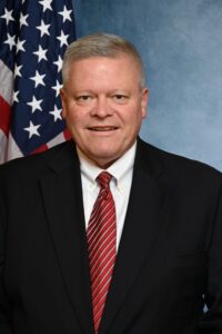 Man in suit with American flag background.