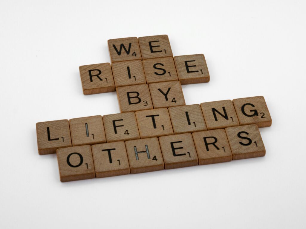 Scrabble letters: We rise by lifting others.