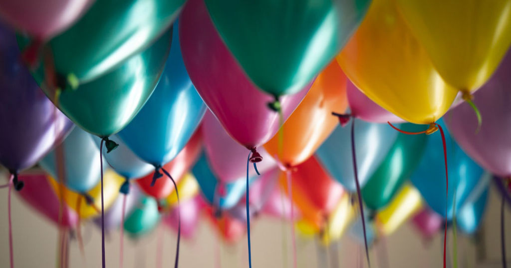 Colorful balloons floating closely together indoors.