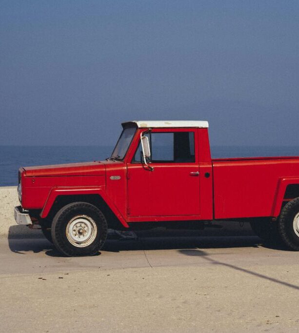 Red pickup truck parked by the ocean