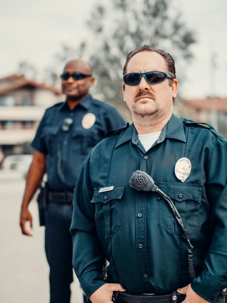 Two police officers standing outside, wearing sunglasses.